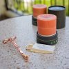 2 hand-poured Aura of Palmarosa pillar candle made with palm wax and natural essential oils with a Palm Lights custom matchbox and a rose gold wick trimmer.