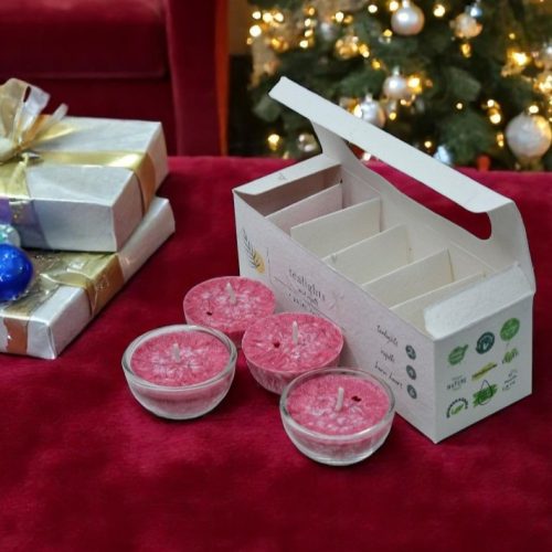 A box of hand-poured Cinnamon Cannon tealights made with palm wax and natural essential oils with a Christmas themed background.