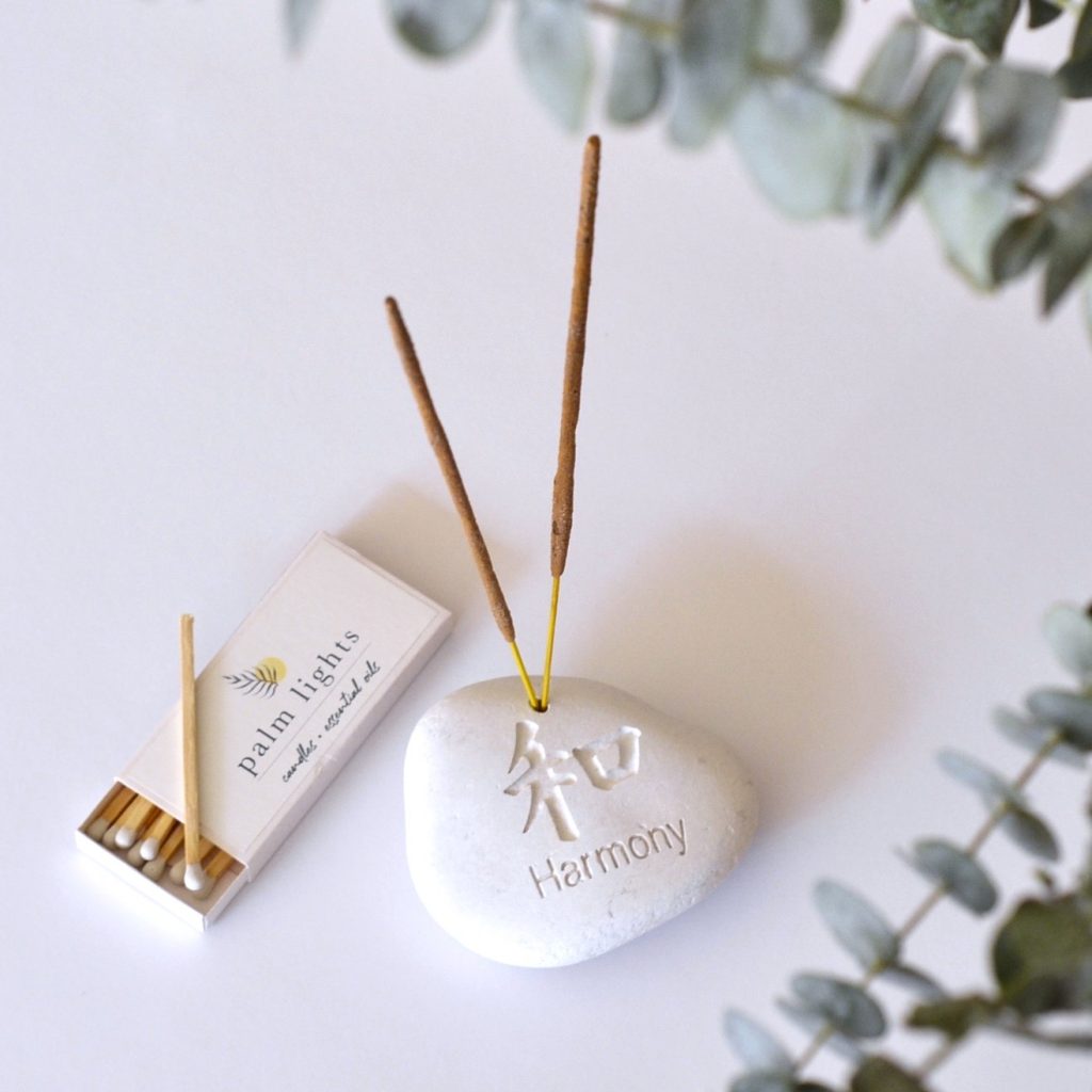 Palm Lights branded matchbox displayed beside a Harmony incense holder with burning incense sticks and eucalyptus leaves.