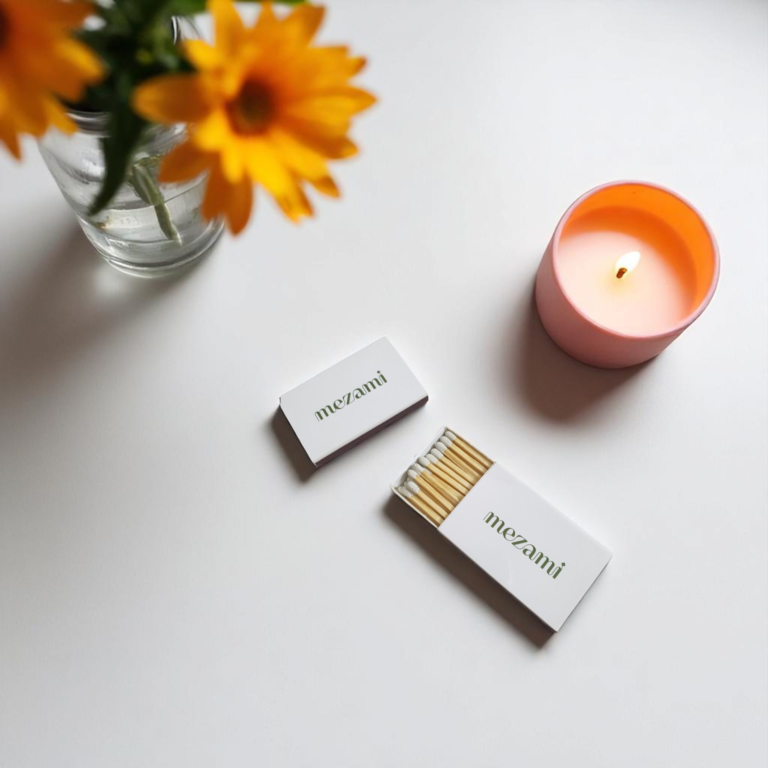Branded wedding matchbox placed beside a lit candle and floral arrangement on a wedding-inspired table setting.